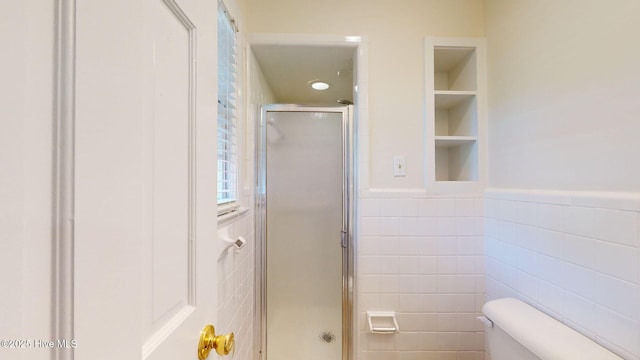 bathroom with built in features, toilet, an enclosed shower, and tile walls