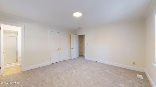 unfurnished bedroom with crown molding, connected bathroom, light colored carpet, and a closet