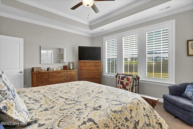 carpeted bedroom with crown molding, ceiling fan, and a tray ceiling