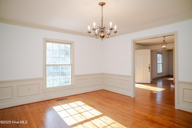 spare room with wood-type flooring, ornamental molding, and a notable chandelier