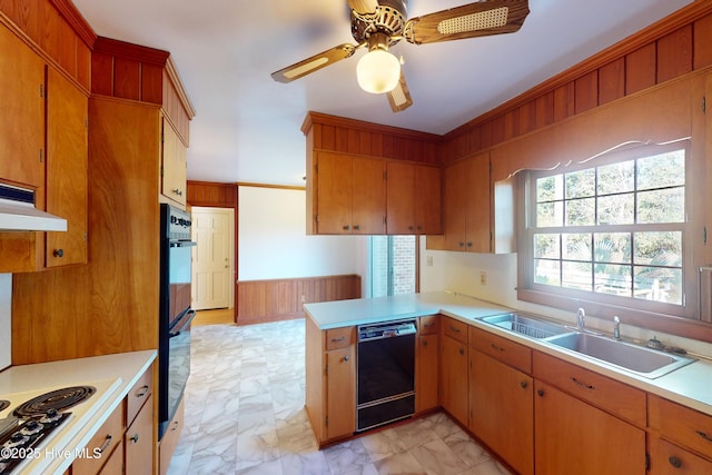 kitchen with sink, ceiling fan, wooden walls, black appliances, and kitchen peninsula