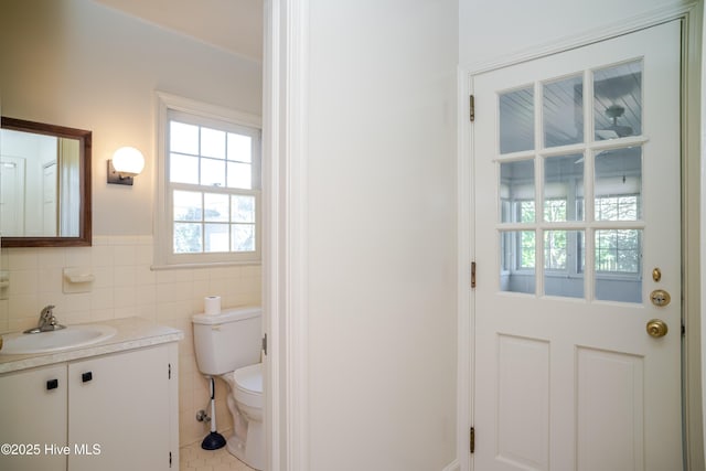 bathroom with vanity, tile patterned flooring, tile walls, and toilet