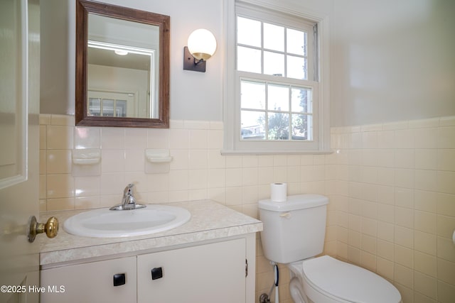 bathroom with vanity, tile walls, and toilet