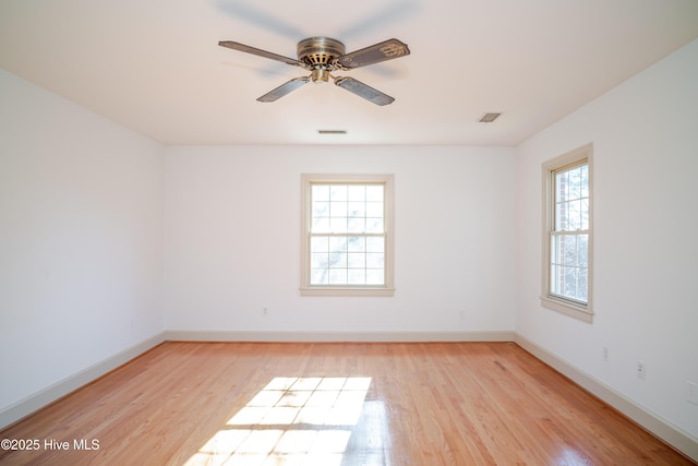 spare room with ceiling fan, a wealth of natural light, and light wood-type flooring