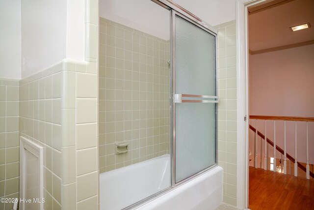 bathroom featuring hardwood / wood-style flooring and shower / bath combination with glass door