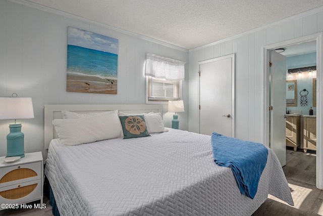 bedroom featuring hardwood / wood-style flooring, ornamental molding, and a textured ceiling