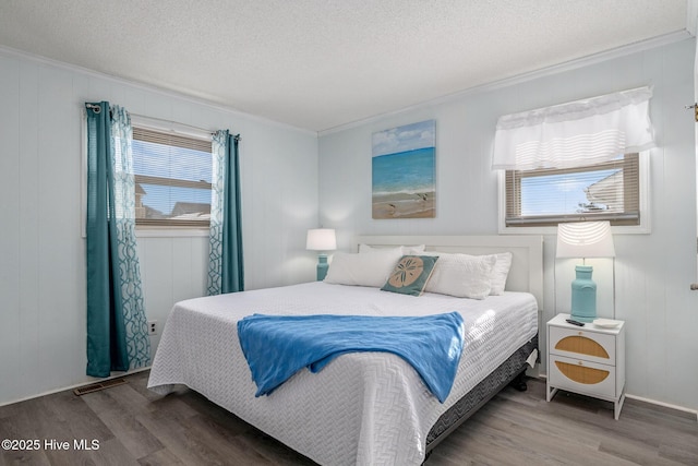 bedroom featuring ornamental molding, wood-type flooring, and a textured ceiling