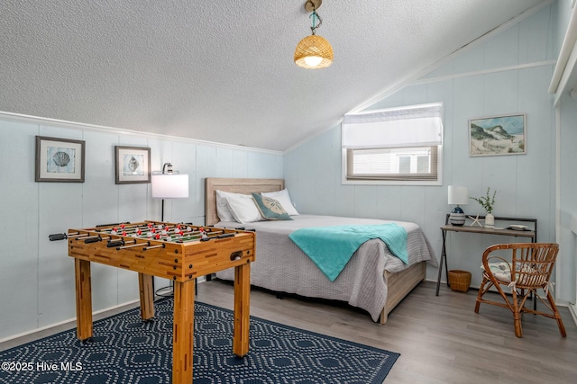 bedroom with hardwood / wood-style flooring, lofted ceiling, and a textured ceiling