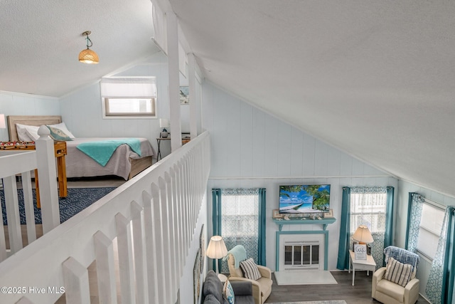 bedroom with hardwood / wood-style flooring, lofted ceiling, multiple windows, and a crib