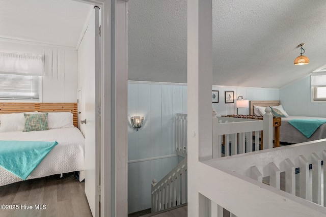 bedroom featuring multiple windows, hardwood / wood-style floors, vaulted ceiling, and wood walls