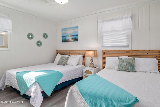 bedroom with wood-type flooring, a textured ceiling, and wood walls