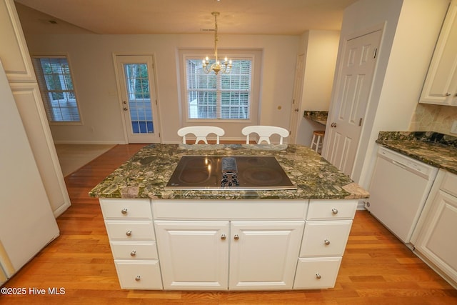 kitchen with white dishwasher, black electric cooktop, a kitchen island, white cabinets, and dark stone counters