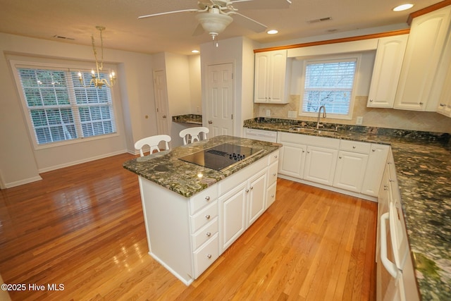 kitchen with white cabinetry, black electric cooktop, a sink, and pendant lighting