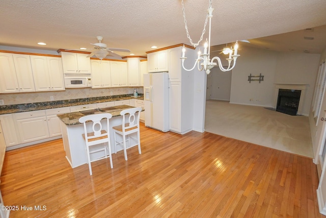 kitchen with white cabinets, white appliances, a kitchen island, and open floor plan