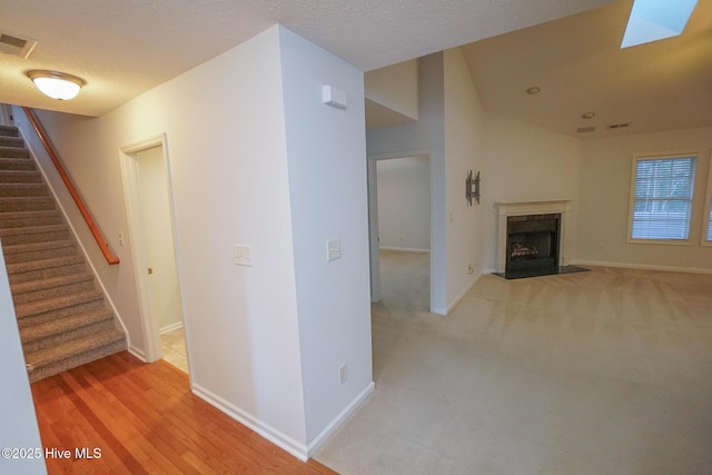 unfurnished living room with visible vents, stairway, a high end fireplace, and baseboards