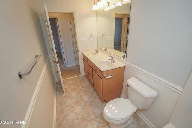 bathroom featuring double vanity, a wainscoted wall, tile patterned flooring, and a sink