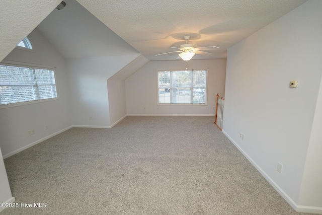 bonus room with light colored carpet, lofted ceiling, a healthy amount of sunlight, and a textured ceiling