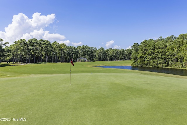 view of home's community with view of golf course, a water view, and a yard