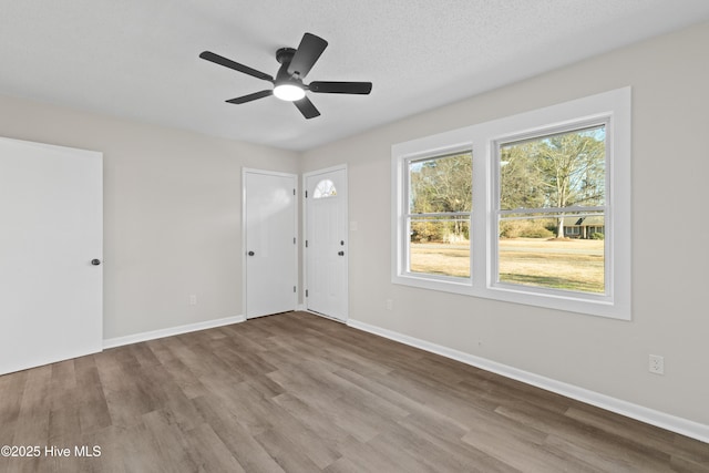 unfurnished room with ceiling fan, wood-type flooring, and a textured ceiling