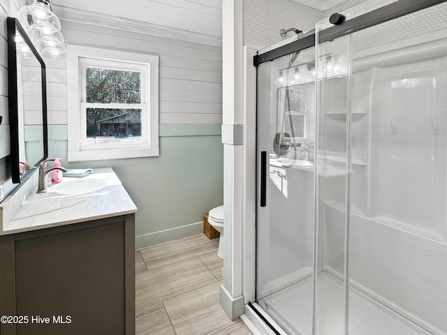 bathroom featuring toilet, a shower with shower door, and vanity