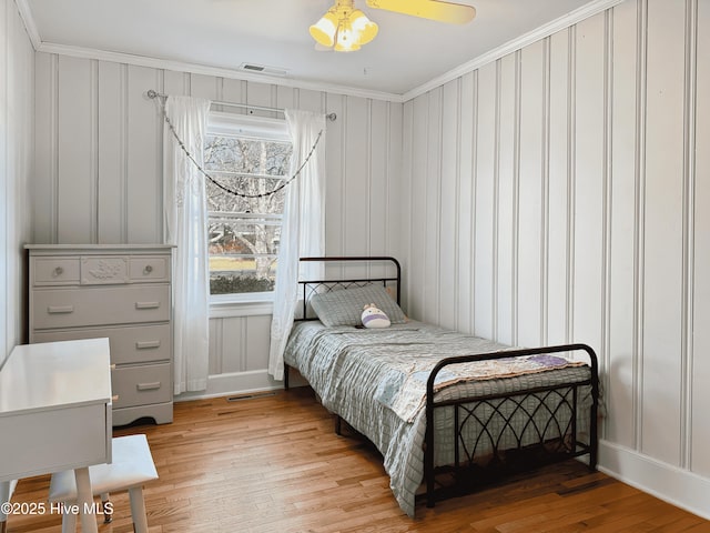 bedroom featuring ceiling fan, ornamental molding, and light wood-type flooring