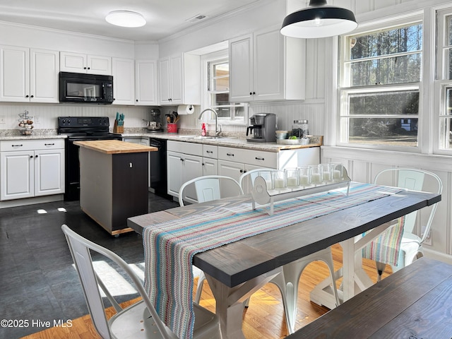 kitchen with crown molding, sink, white cabinetry, a center island, and black appliances