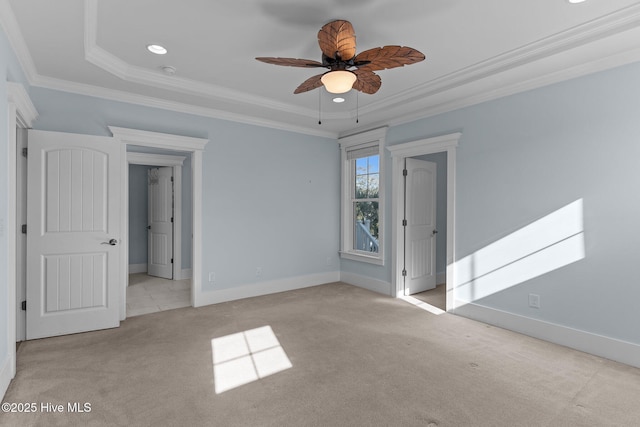 empty room with ceiling fan, light colored carpet, crown molding, and a raised ceiling