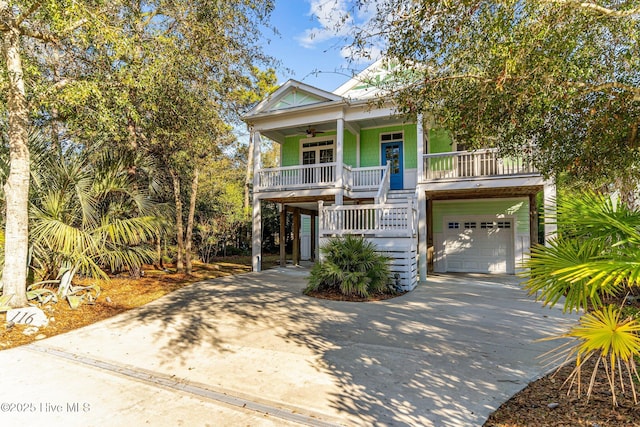 raised beach house featuring covered porch, a garage, and ceiling fan