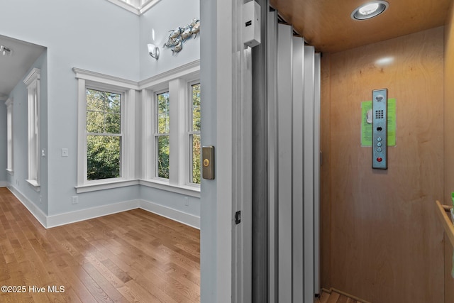 hallway with elevator and light hardwood / wood-style flooring