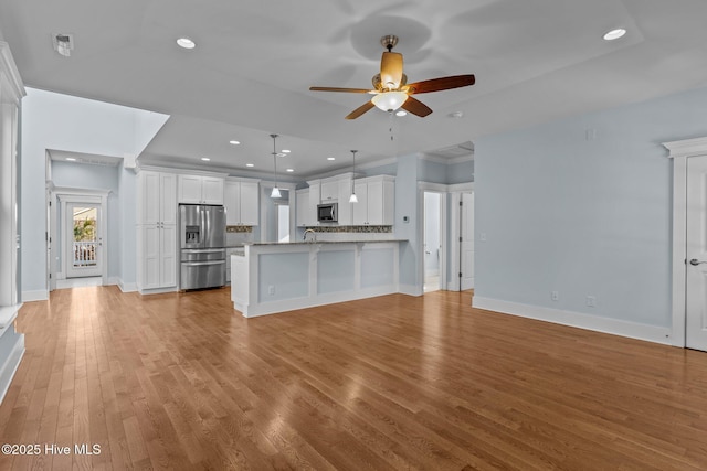 kitchen with ceiling fan, hanging light fixtures, white cabinets, decorative backsplash, and stainless steel appliances