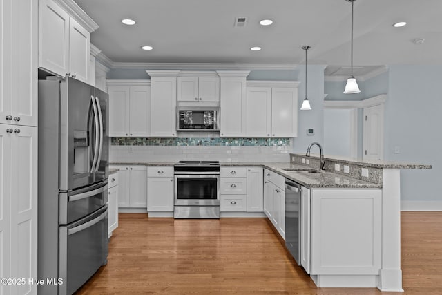 kitchen with kitchen peninsula, appliances with stainless steel finishes, sink, decorative light fixtures, and white cabinets