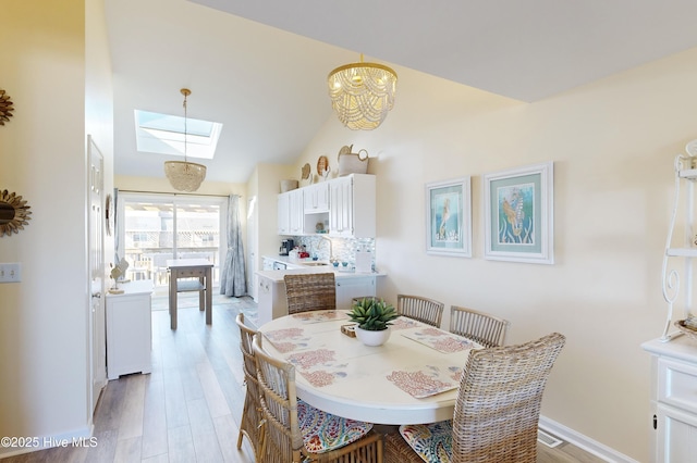 dining area featuring sink, lofted ceiling with skylight, and light hardwood / wood-style floors