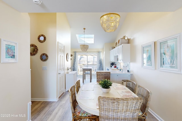 dining room with sink, light hardwood / wood-style flooring, and a skylight