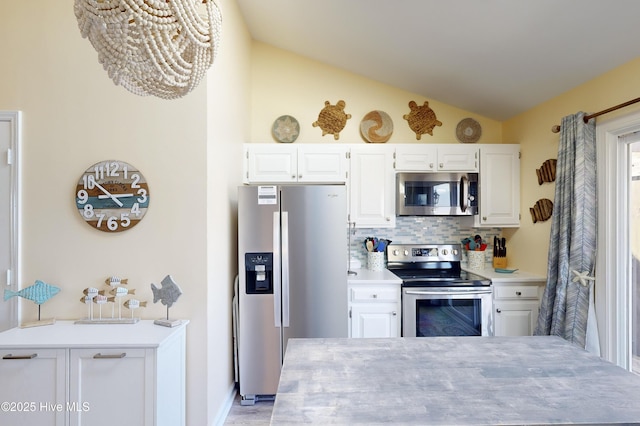 kitchen with stainless steel appliances, white cabinetry, vaulted ceiling, and backsplash