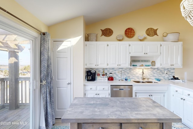 kitchen featuring lofted ceiling, sink, white cabinetry, stainless steel dishwasher, and decorative backsplash