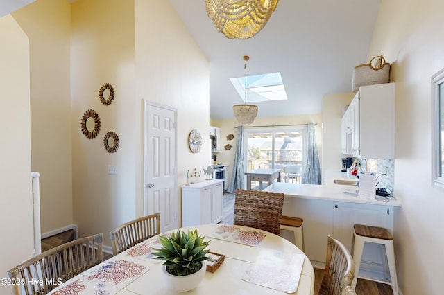 dining area with hardwood / wood-style floors, high vaulted ceiling, and a skylight