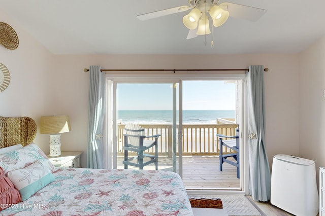 bedroom with multiple windows, access to outside, light hardwood / wood-style flooring, and a water view