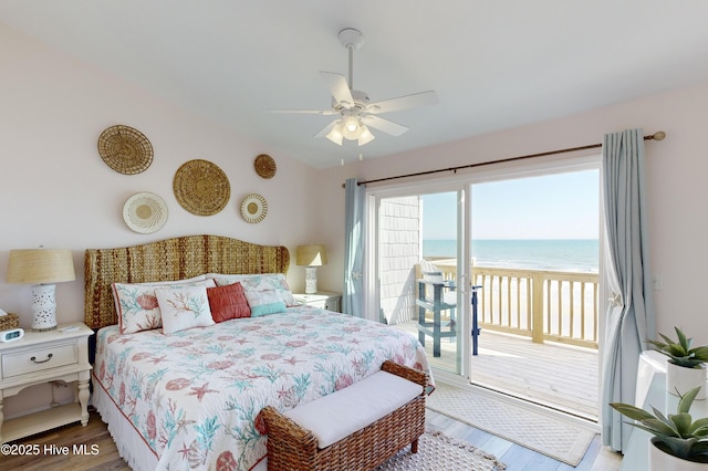 bedroom with a beach view, a water view, vaulted ceiling, access to outside, and hardwood / wood-style flooring