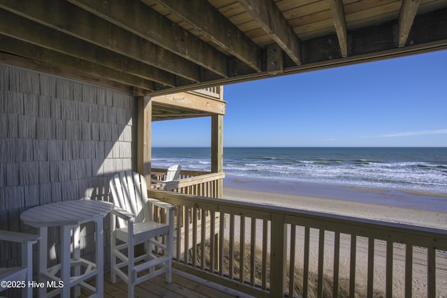 wooden terrace featuring a beach view and a water view