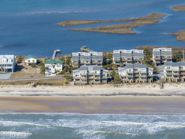 aerial view at dusk featuring a view of the beach and a water view