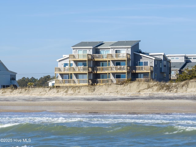 back of house featuring a water view and a beach view