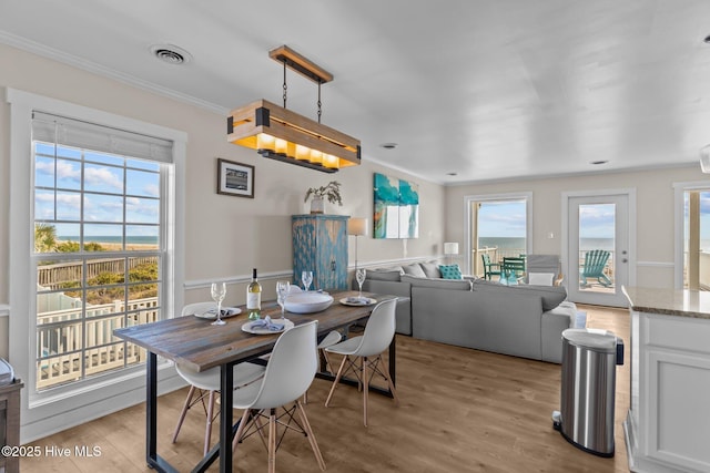 dining space with ornamental molding and light hardwood / wood-style floors