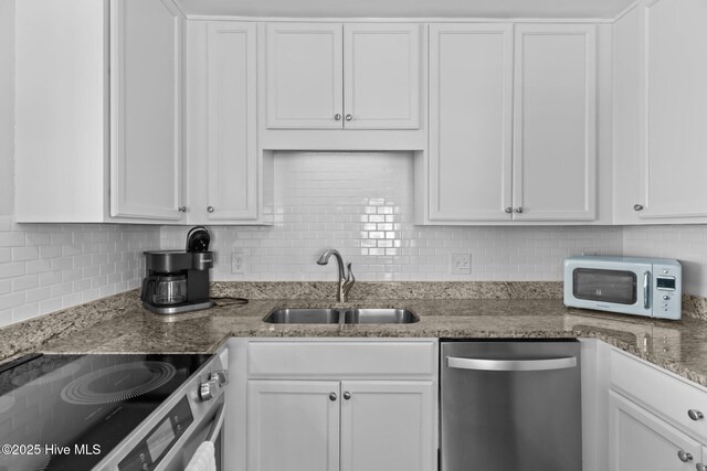 173 Ocean Blvd W # A, Holden Beach, NC 28462 - kitchen with dishwasher, a sink, white microwave, backsplash, and white cabinetry