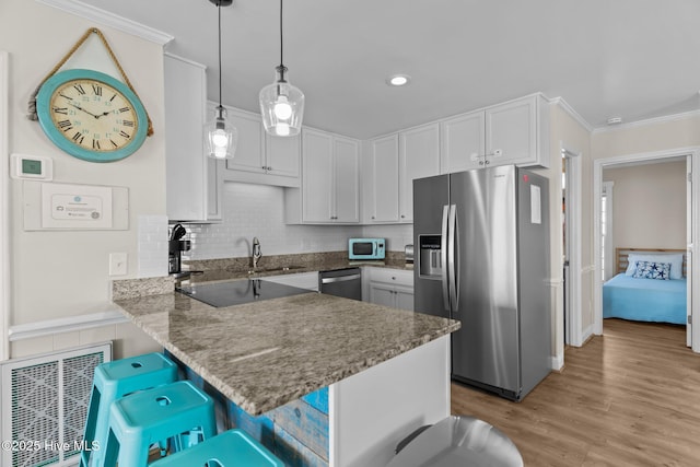 kitchen featuring white cabinetry, appliances with stainless steel finishes, a kitchen breakfast bar, kitchen peninsula, and pendant lighting