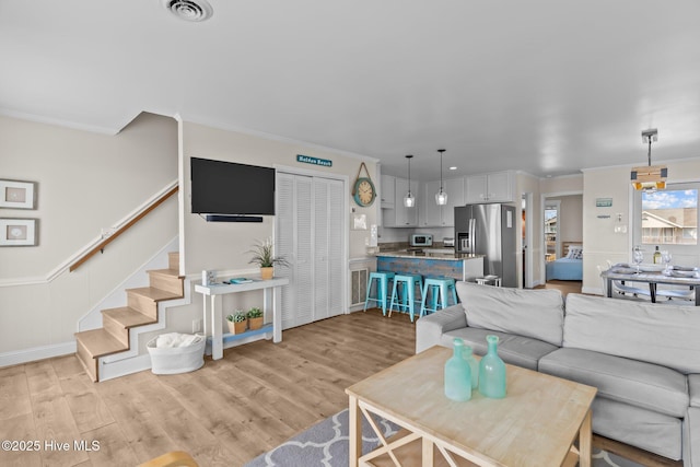 living room with ornamental molding and light hardwood / wood-style flooring