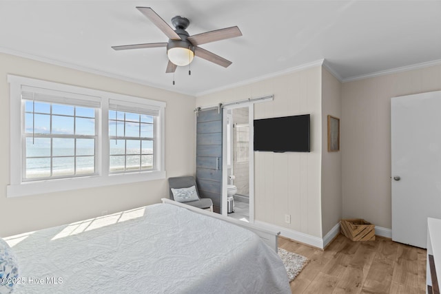 bedroom with crown molding, light hardwood / wood-style flooring, ensuite bath, a water view, and a barn door