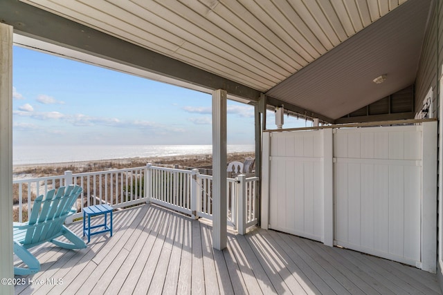 wooden terrace featuring a water view and a beach view