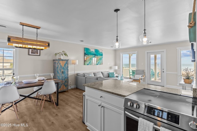 kitchen with decorative light fixtures, white cabinets, light hardwood / wood-style floors, and stainless steel electric range