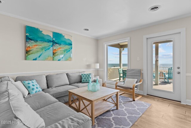 living room with crown molding, a water view, and light hardwood / wood-style floors