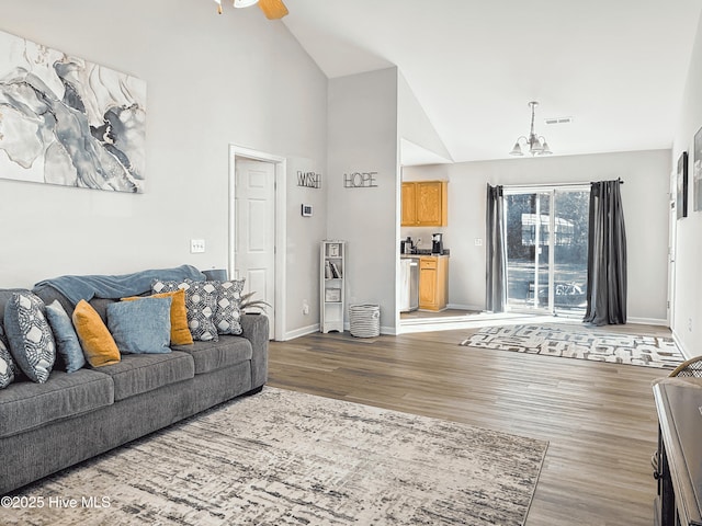 living room featuring high vaulted ceiling, dark hardwood / wood-style floors, and ceiling fan with notable chandelier